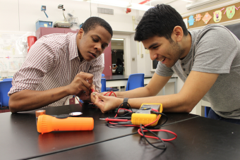 Two male students work with batteries
